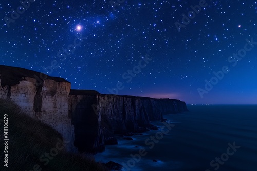 Bright star filled sky above coastal cliff the constellation of Orion visible against a backdrop of deep blue to black gradient sky stars glimmering rugged cliffs illuminated by moonlight