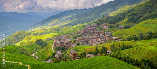 Fotografie The village surrounded by lush green rice fields in Longji rice terraces, Guangx