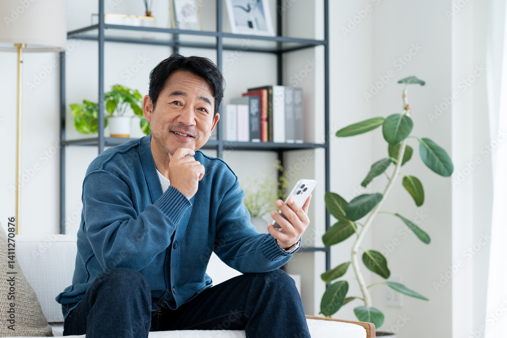 Naklejka premium リビングでスマホを使うミドルの男性
