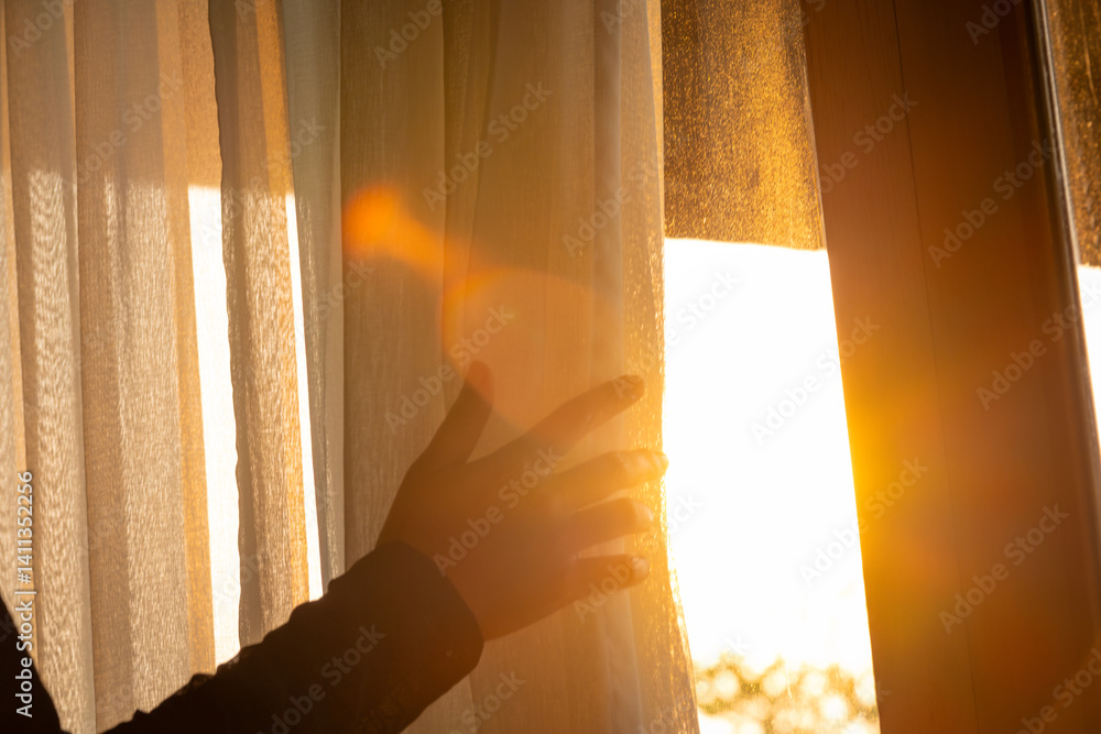 woman's hand She opened the curtains on the window. There was morning light through the window in her room, looking at the view of the mountains and trees as the sun rose