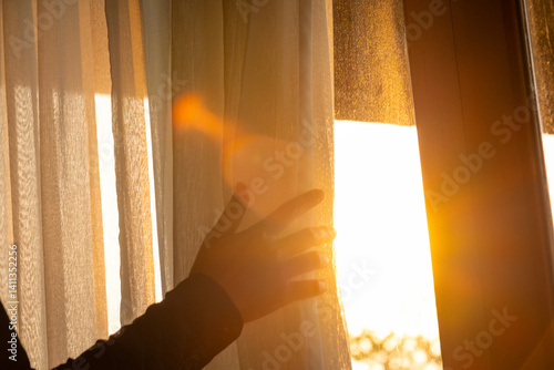 Obraz na płótnie woman's hand She opened the curtains on the window. There was morning light through the window in her room, looking at the view of the mountains and trees as the sun rose w salonie