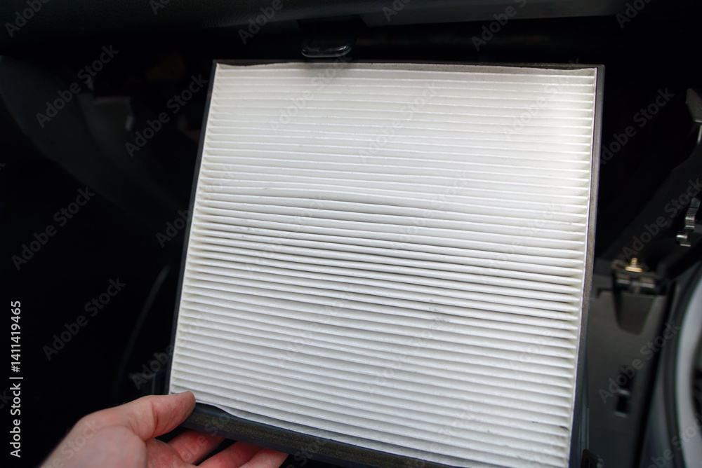Hand with new clean cabin air filter, ready to install inside the glovebox of car as part of routine maintenance to improve air quality, ventilation. New cabin air filter installation. Selective focus