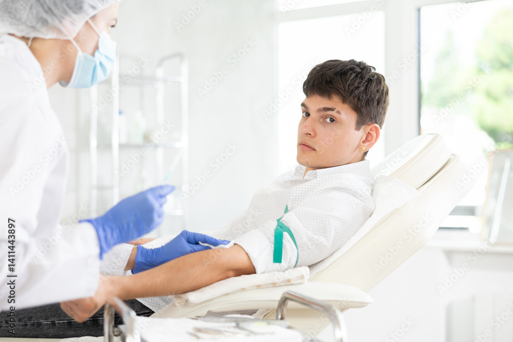 Obraz premium Anesthesiologist doctor injecting pain medication into vein of man before starting surgery in a cosmetology clinic