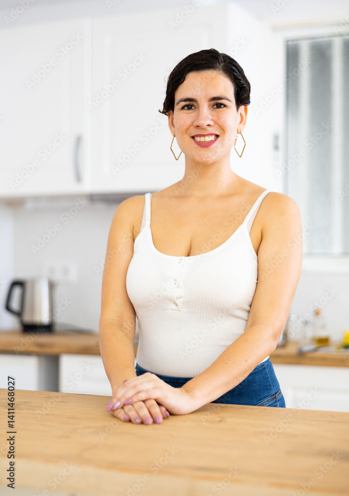 Portrait of positive girl housewife standing at home kitchen Portrait of positive girl housewife standing at home kitchen