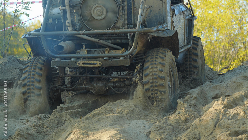 A muddy off-road vehicle navigates a challenging sandy terrain. The vehicle's tires are deeply embedded in the sand, and the suspension is flexed as it climbs the slope. A muddy off-road vehicle navigates a challenging sandy terrain. The vehicle's tires are deeply embedded in the sand, and the suspension is flexed as it climbs the slope.
