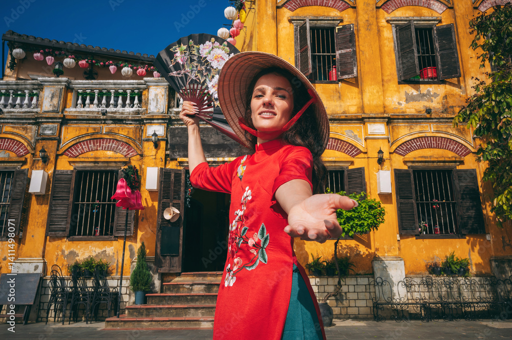 Fototapeta premium Portrait of a young woman in a traditional costume of Vietnamese culture in the ancient Hoi An area, Vietnam