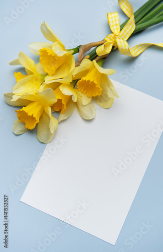 Bouquet of daffodils with greeting card lying on blue table