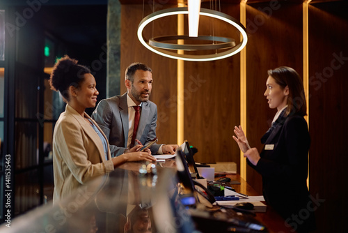 Foto Business colleagues talking to receptionist while checking in at hotel