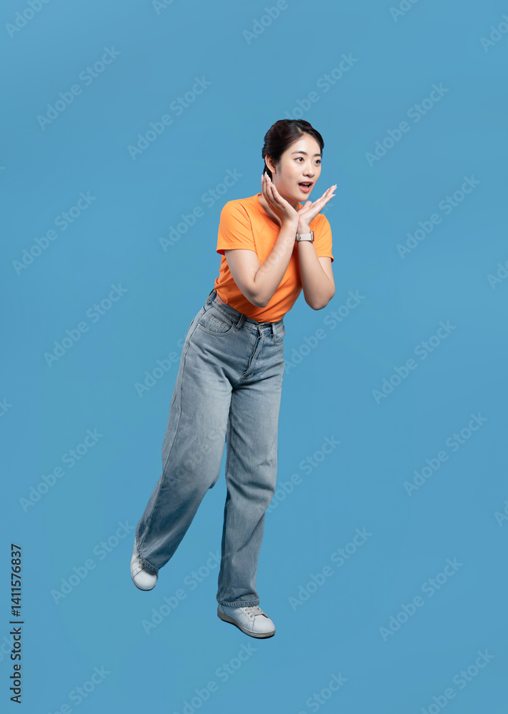 Surprised woman in orange shirt with hands on cheeks gazing at something amazing with delight Surprised woman in orange shirt with hands on cheeks gazing at something amazing with delight