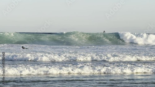 surfers catching large waves at famous popular Bondi beach. Powerful Pacific Ocean overlooking the massive cliffs and houses. Sydney, New South Wales, Australia.