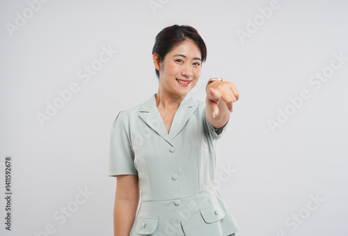 Obraz na plátne Smiling woman in a light green suit points directly at the viewer with a friendl
