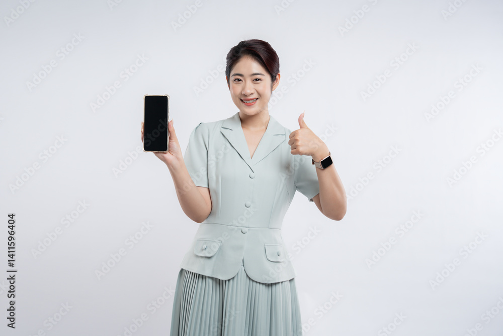 Cheerful Woman Shows Smartphone and Thumbs Up for Approval Against Plain Backdrop Wearing Smartwatch Cheerful Woman Shows Smartphone and Thumbs Up for Approval Against Plain Backdrop Wearing Smartwatch