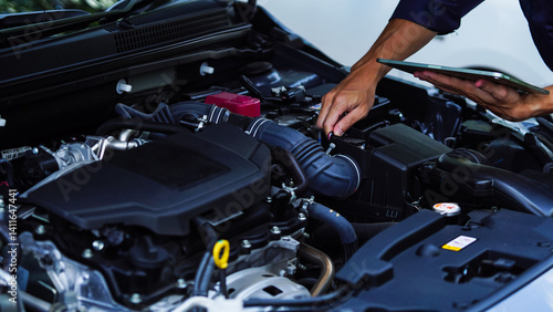 Mechanic in work gloves repairs car engine in auto repair shop. Auto mechanic checks vehicle with wrench, fixes issues. Car service, maintenance, engine diagnostic, automotive repair.