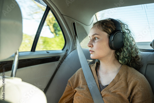 Teen age girl in the car with headphones, listening music