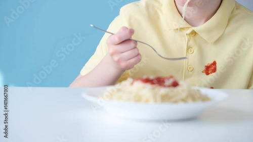 Spilled tomato sauce or ketchup on yellow clothes. Unrecognizable person eating spaghetti. The cheerful atmosphere highlights a joyful lunchtime moment.