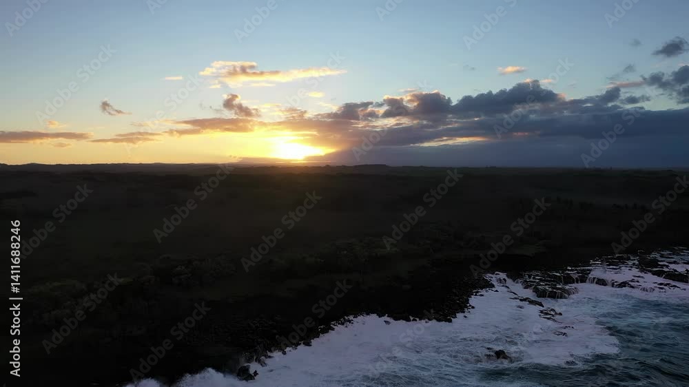 Sun sets over the Pacific Ocean, casting a golden glow across the rugged Hawaiian coastline. Waves crash below as evening light colors the sky and sea. Sun sets over the Pacific Ocean, casting a golden glow across the rugged Hawaiian coastline. Waves crash below as evening light colors the sky and sea.