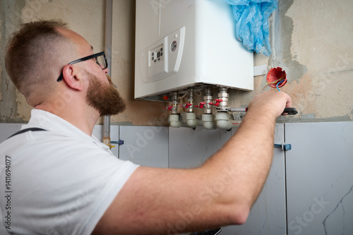 Plumber Install a Boiler. Professional engineer installing gas boiler at home and checking the connections and pipes of the domestic heating system. Boiler Installation Service adjusting heating 