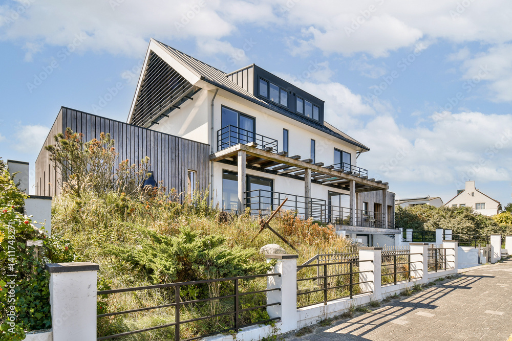 Fototapeta premium A stunning modern house featuring sleek lines and large windows, elegantly set amidst lush greenery and neat landscaping, exemplifying contemporary living.
