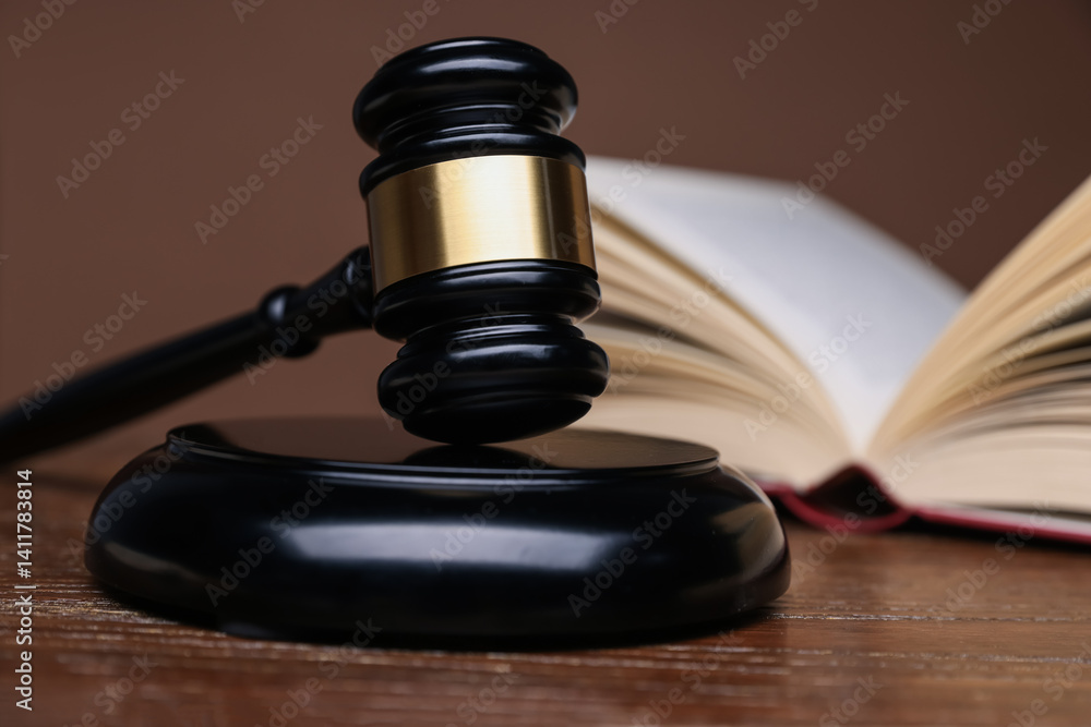 Judge's gavel, sound block and book on wooden table against brown background, closeup Judge's gavel, sound block and book on wooden table against brown background, closeup