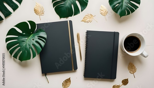 Top view of a black notebook mockup with  workspace accessories and a monstera leaf on a white table.