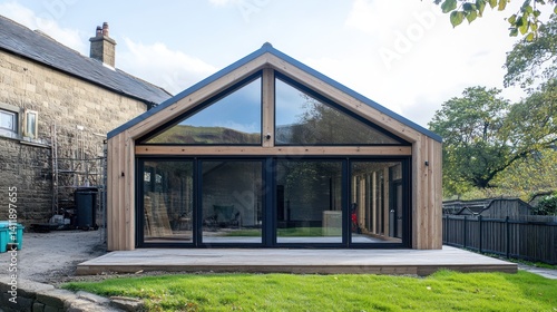 A wooden house extension under construction with large windows and an eco-friendly design.