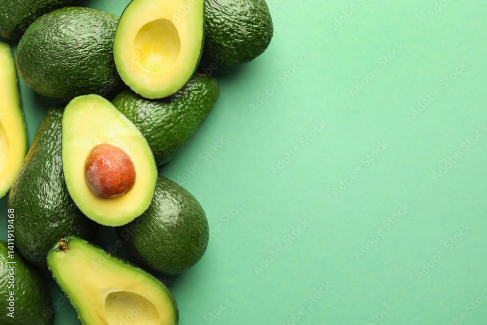 Whole and cut avocados on green background, flat lay. Space for text