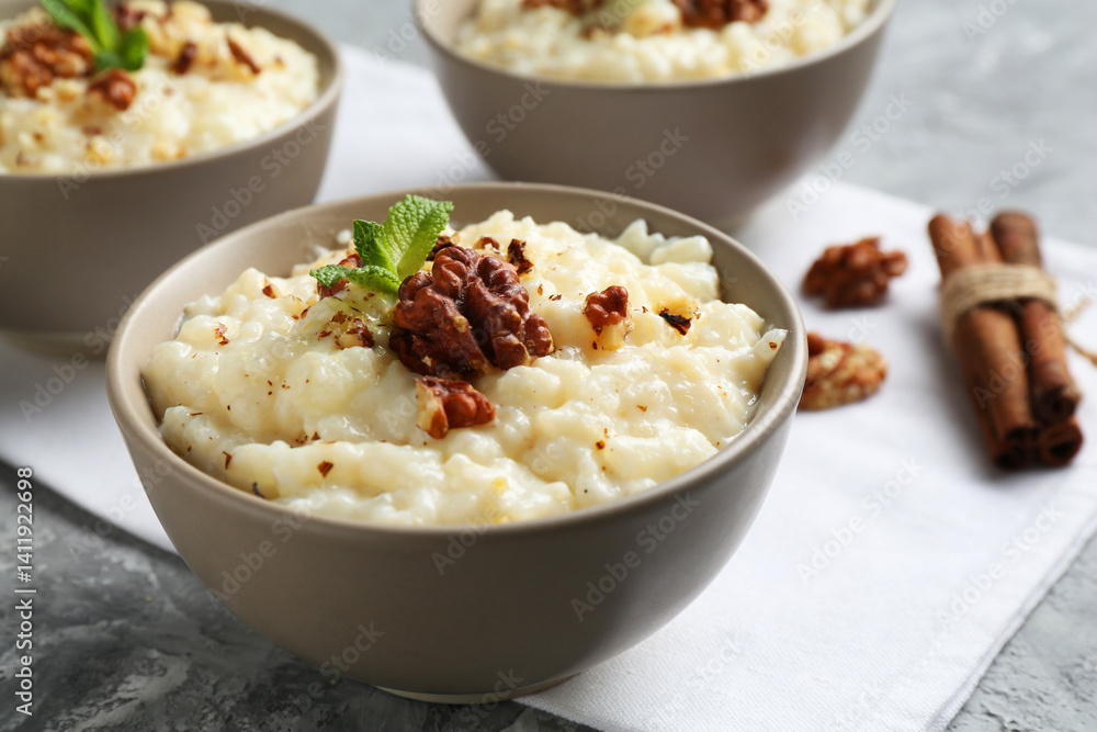 Delicious rice pudding with walnuts, mint and cinnamon on grey table, closeup Delicious rice pudding with walnuts, mint and cinnamon on grey table, closeup