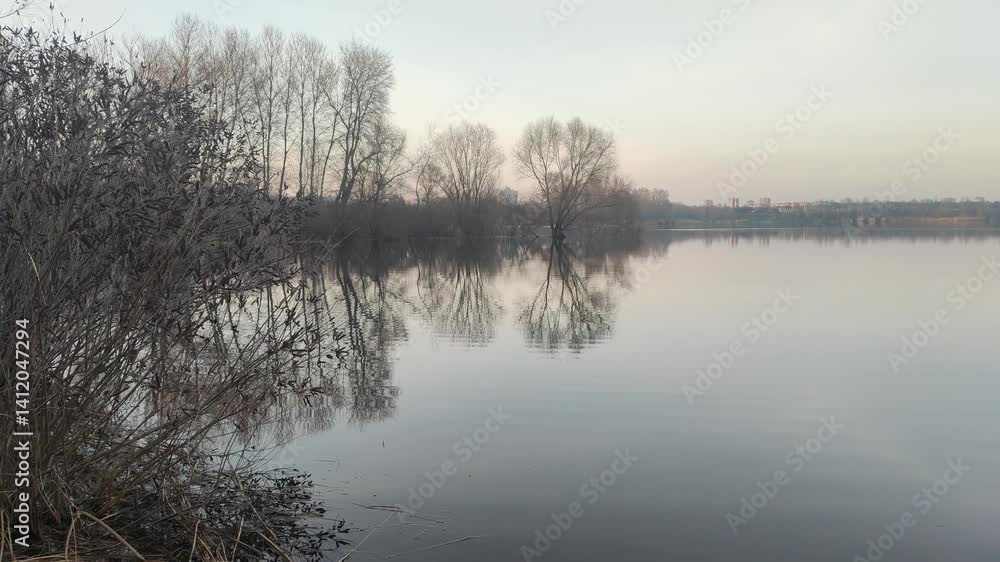 vertical video. evening landscape on the river with reflection in the water. The colorful cloudy sky and trees are reflected in the calm river water. Grass and trees grow on the banks of the river. vertical video. evening landscape on the river with reflection in the water. The colorful cloudy sky and trees are reflected in the calm river water. Grass and trees grow on the banks of the river.