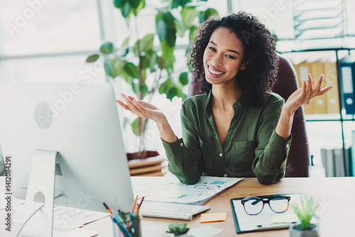 Confident young businesswoman in casual attire smiling at her office desk