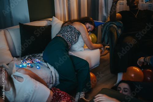 Obraz na płótnie Individuals relaxing on couches and floor among party remnants, showcasing a natural post-event vibe with balloons and decorations indicative of a vibrant celebration. w salonie
