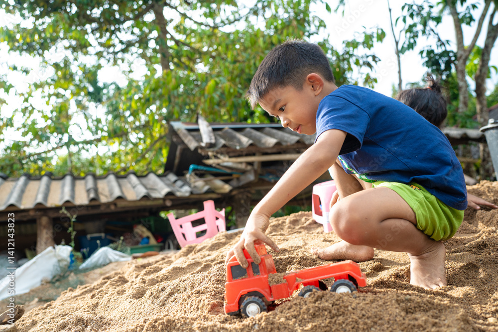Little school boy play toy on sand at home outdoor activity