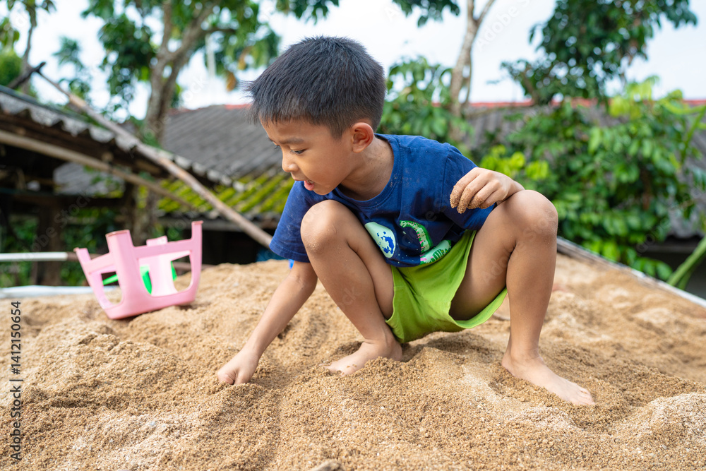 Little school boy play toy on sand at home outdoor activity