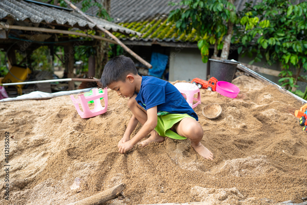 Little school boy play toy on sand at home outdoor activity