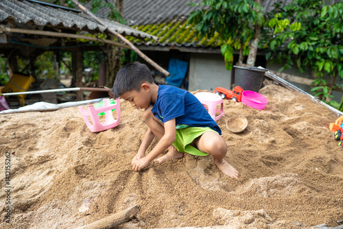 Little school boy play toy on sand at home outdoor activity