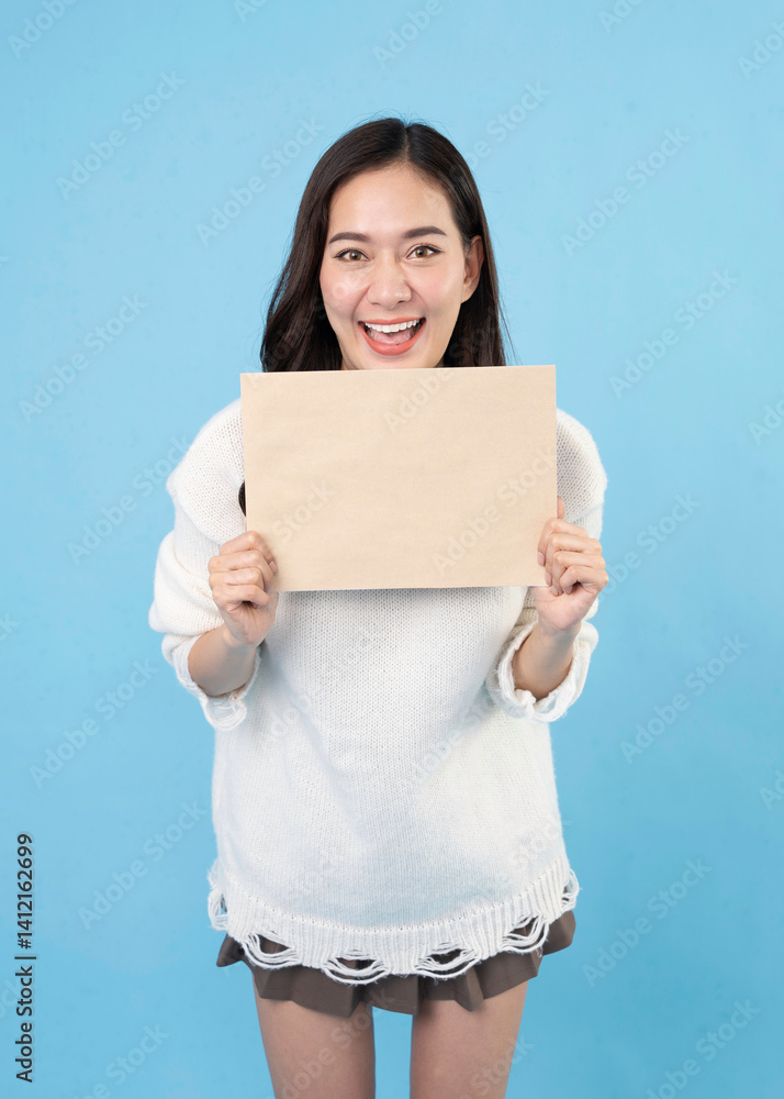 Your text here. Young excited woman holding empty blank board. Colorful studio portrait with light blue background. Woman holding blank empty banner pointing finger to one self smiling happy and proud Your text here. Young excited woman holding empty blank board. Colorful studio portrait with light blue background. Woman holding blank empty banner pointing finger to one self smiling happy and proud