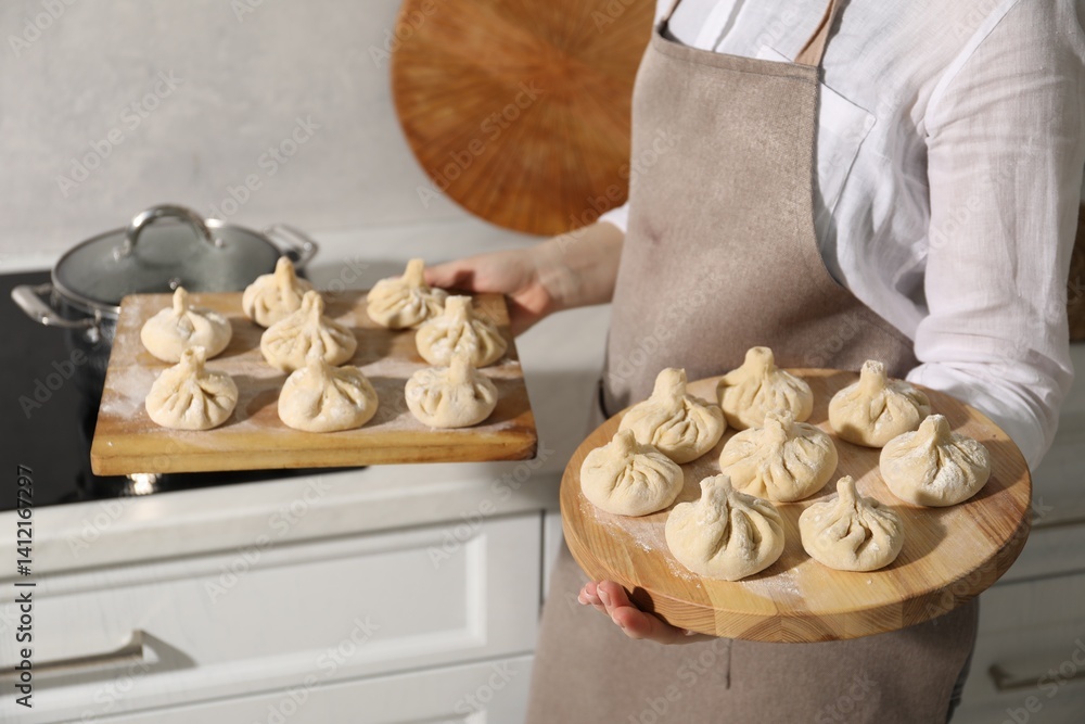 Fototapeta premium Woman with many uncooked khinkali in kitchen, closeup