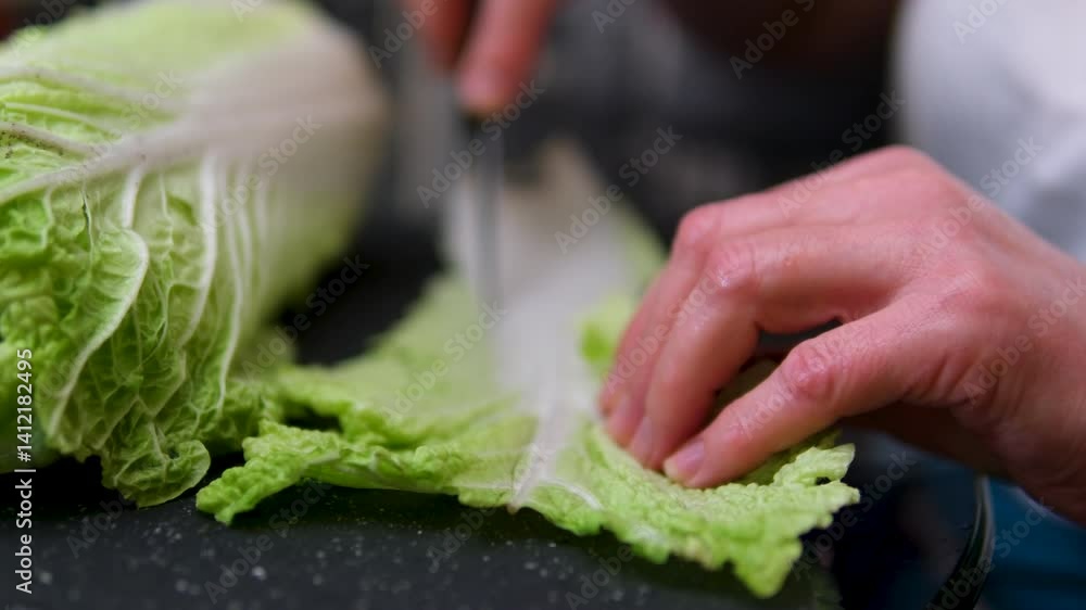 Chinese cabbage is being sliced on a blue cutting board, ready for cooking, with a stainless steel bowl nearby. High quality 4k footage Chinese cabbage is being sliced on a blue cutting board, ready for cooking, with a stainless steel bowl nearby. High quality 4k footage