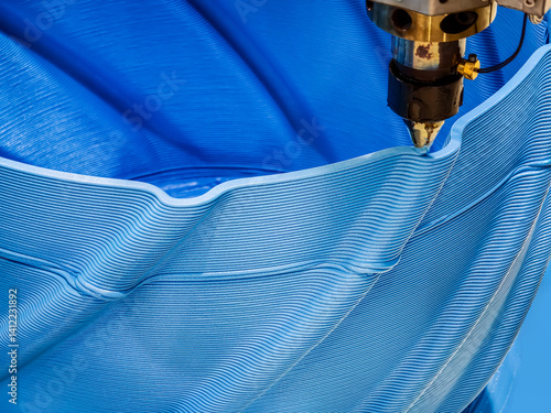 Advanced 3D printing process creates intricate blue patterns in a flexible material on a production line
