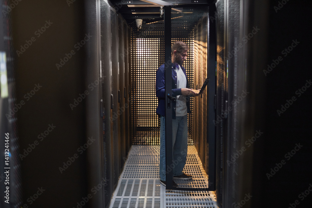 Technician performing routine maintenance in server room with various devices and gadgets around concentrating on task in data center environment Technician performing routine maintenance in server room with various devices and gadgets around concentrating on task in data center environment