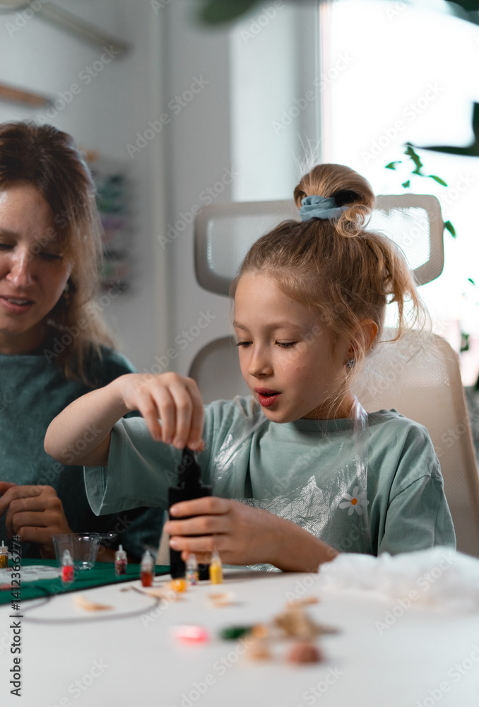 Fototapeta premium Crafting session features tools, UV resin, and various embellishments as mother guides daughter in creating custom trinkets. Artistic process strengthens their bond. Chemistry experiments at home