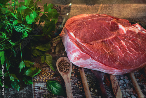 Obraz na płótnie Raw beaf steak with parsley on cutting board. Raw meat, herbs and vegetable on table. Kitchen interior. Steak preparation process. Food styling. Marble steak on cutting board. w salonie