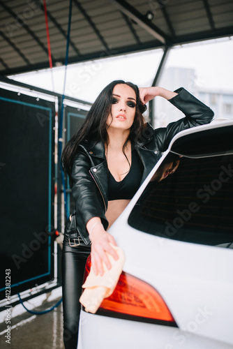 Sexy woman washing car in leather outfit