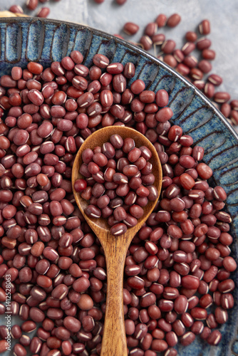 Obraz na płótnie Blue plate full of dried red azuki beans with a wooden spoon top view. Vegetarian protein source w salonie