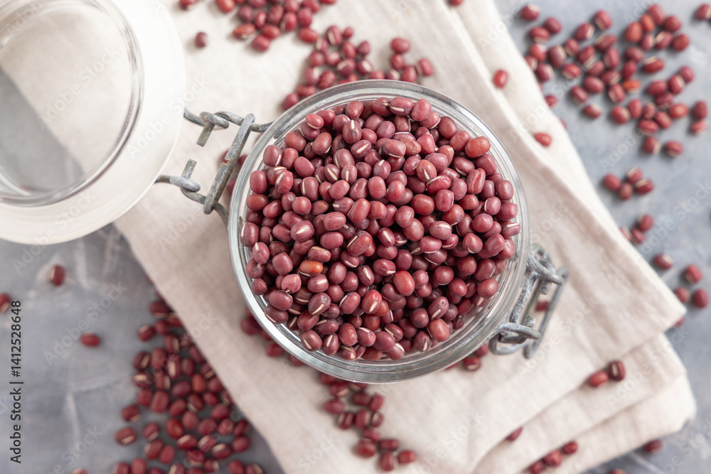 Glass jar full of azuki beans on gray top view. Dried uncooked legumes. Vegetarian protein