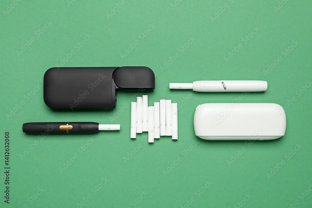 Naklejka premium Composition with different electronic cigars and sticks on green background