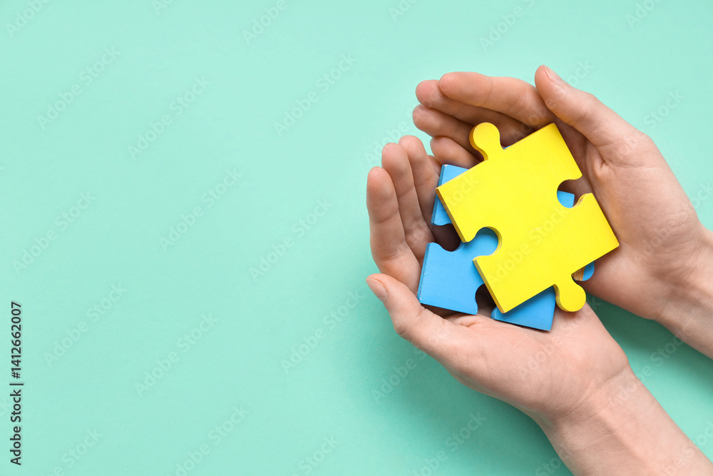 Female hands holding color puzzle on cyan background. Autistic disorder concept