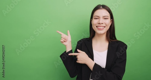 Happy young business woman showing something or copy space for product or sign text. Isolated on green background in studio.