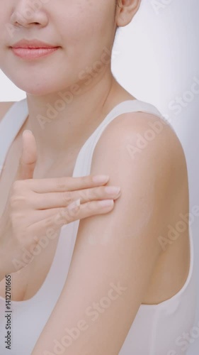 Vertical clip. Young woman applying cosmetic cream on her body.