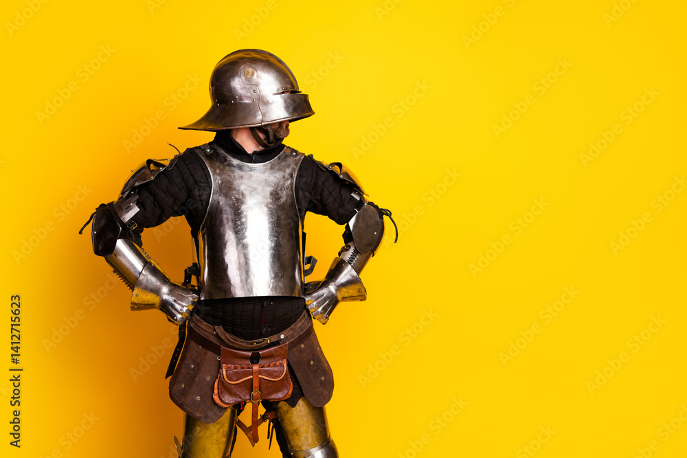 Young man in shiny medieval armor with bold yellow background Young man in shiny medieval armor with bold yellow background