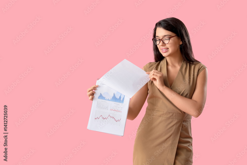 Young beautiful businesswoman in eyeglasses holding clipboard with graphs on pink background Young beautiful businesswoman in eyeglasses holding clipboard with graphs on pink background
